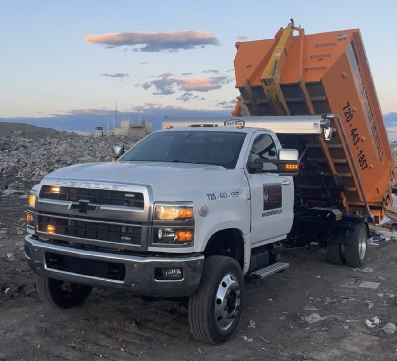 Photo of an orange roll off dumpster at a landfill