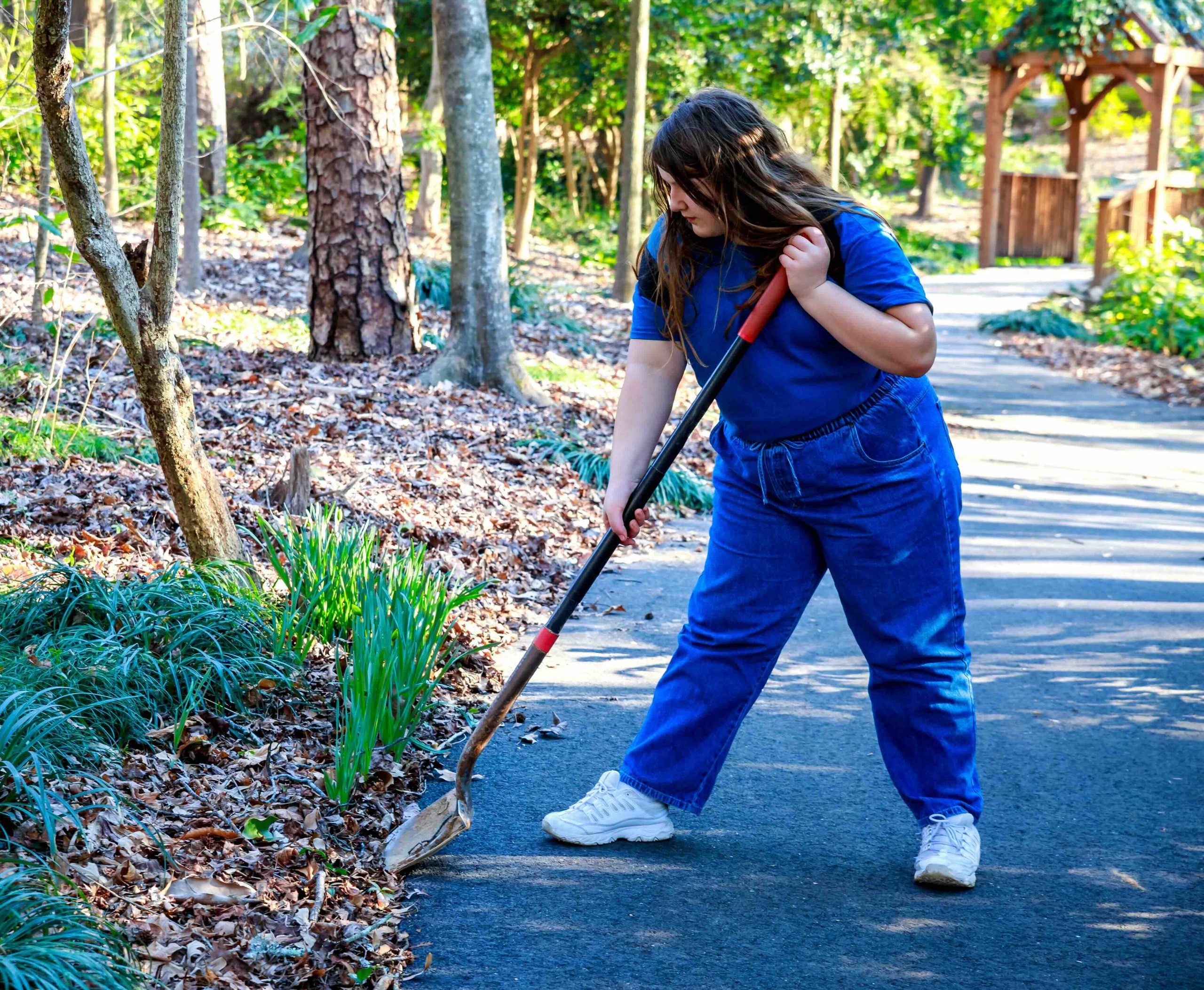 A photo of a woman working on a yard cleanup project.